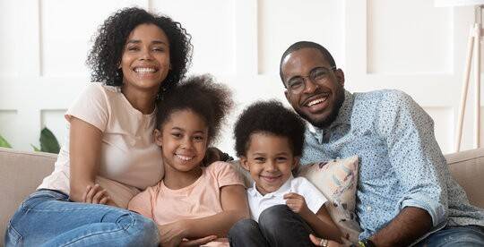Family of four on couch, illustrating protection that whole life insurance provides