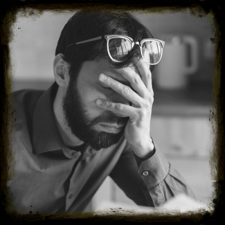 Black and white image of a man with hand over face, symbolizing the financial stress left behind for loved ones when there's no life insurance.