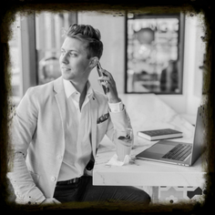 Young professional in business attire working remotely on laptop and phone, representing career opportunities and modern work culture.