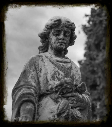 Black and white photo of an old statue covered in patina and moss in a cemetery, conveying the solemn theme of burial insurance.