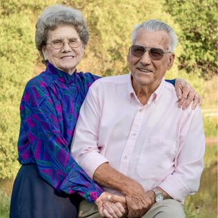 Elderly couple holding hands and smiling after decades of marriage, symbolizing lasting love, connection, and longevity.