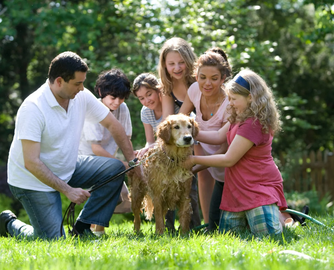 Happy family washing their golden retriever dog together in the backyard on a sunny day – symbolizing love, protection, and the importance of family life insurance.