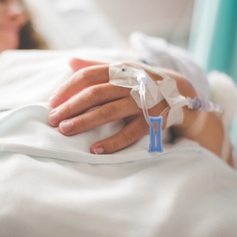 Hand with IV in hospital setting, blurred background, symbolizing how accidental benefits can enhance a primary life insurance policy during unexpected events