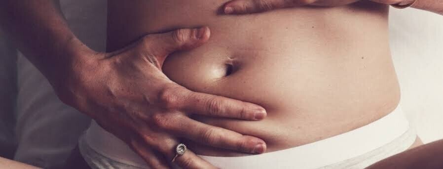 Mani di donna  che eseguono un autotrattamento Yam ( Abdominal Therapy )  per regolare il proprio sistema nervose e prendersi cura della propria salute globale e della propria ciclicità e fertilità).