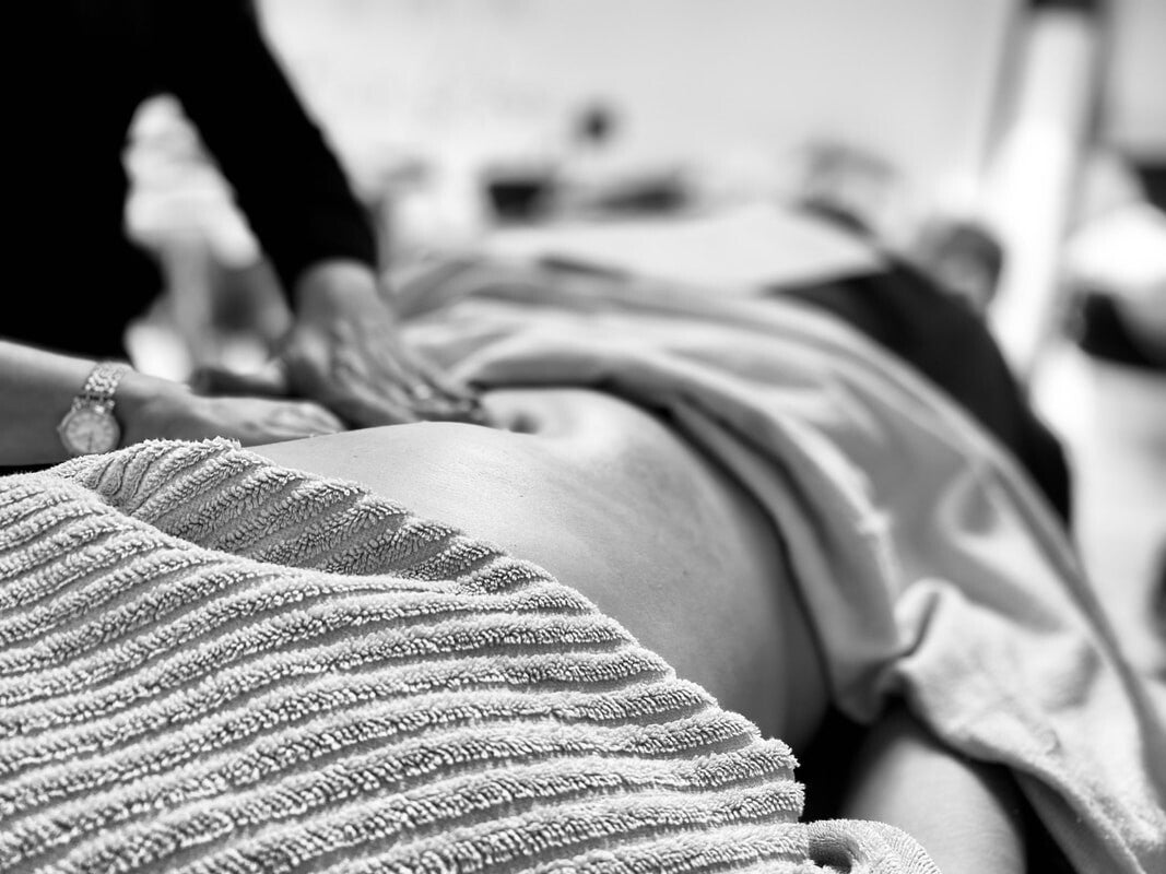 Mani delicate posizionate sull'addome in un gesto di ascolto e ostegno della salute ormonale, ciclica e riproduttiva.