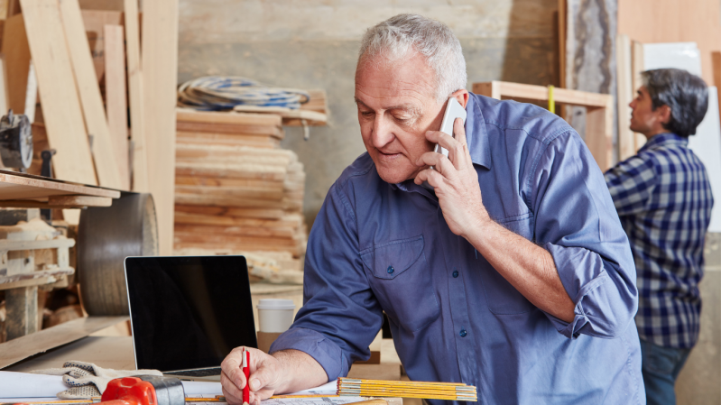 Artisan au téléphone dans son atelier tout en gérant son activité