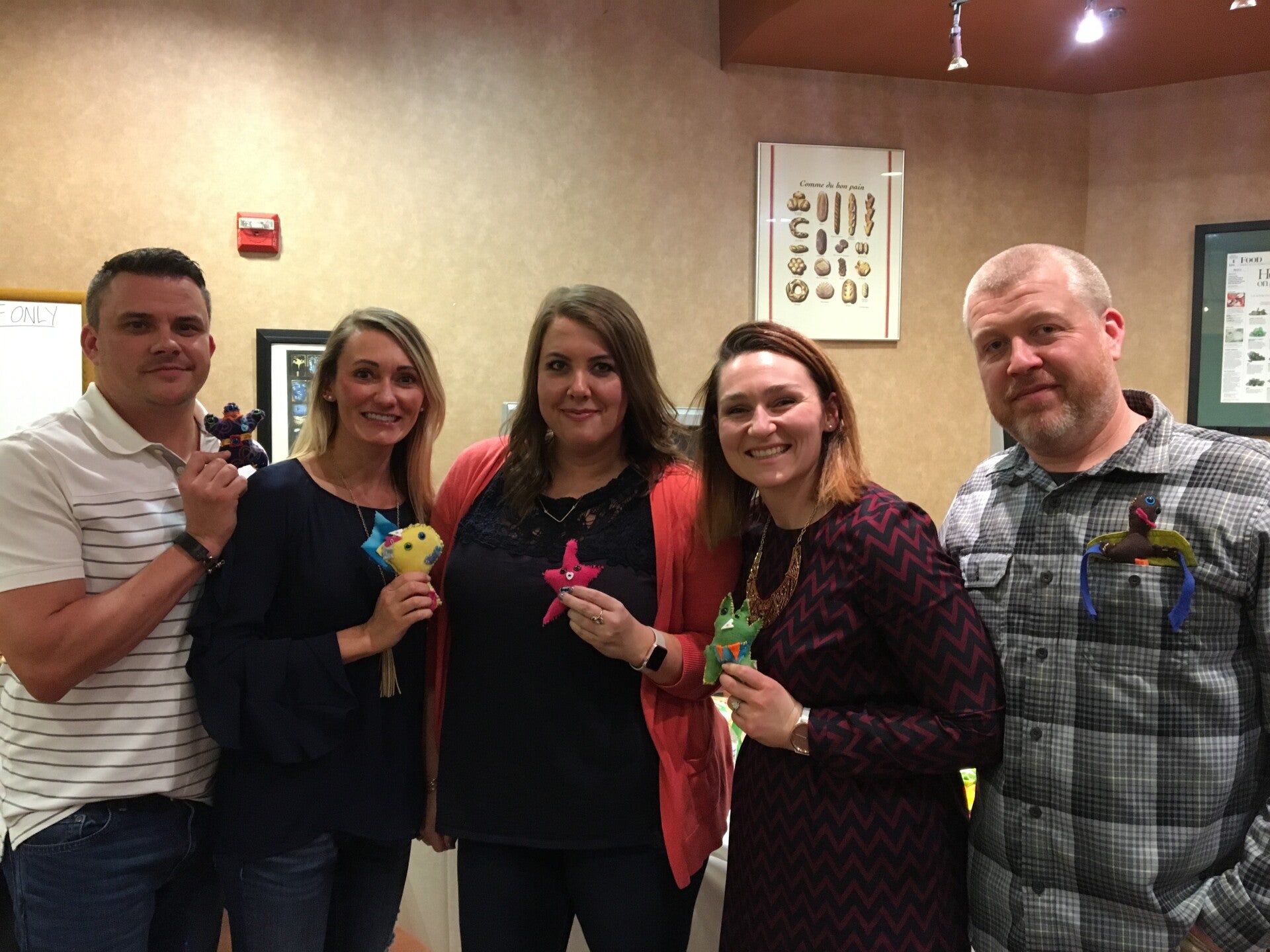 Five adults smiling and holding colorful handmade plush monsters.