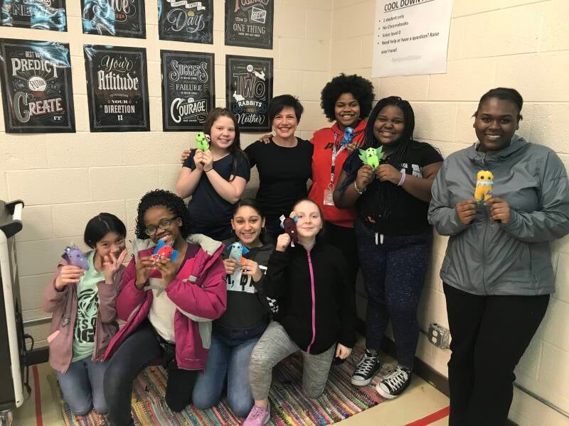 Group of people smiling and holding handmade plush monsters.