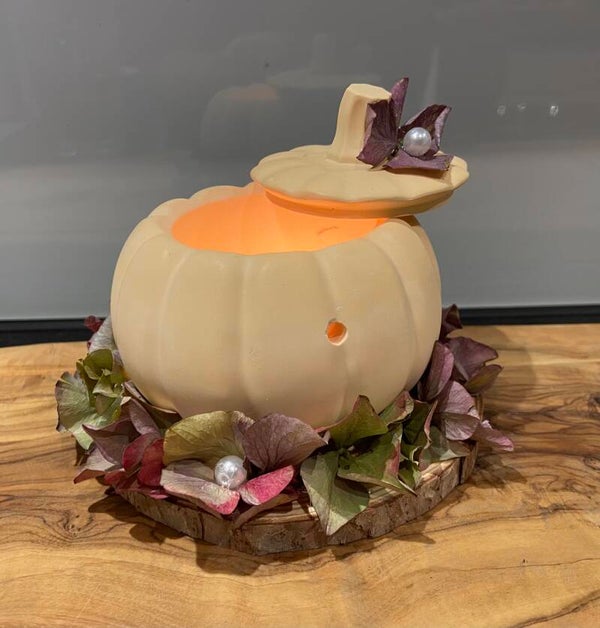 Kürbislicht auf Holzscheibe mit Hortensien