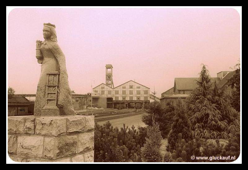 Sint barbara beeld met op de achtergrond de gebouwen en de schacht van de Oranje Nassau Mijn 4, de foto is uit 1952. © Nico./www.gluckauf.nl