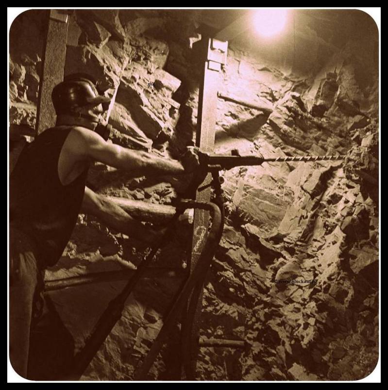 Houwer achter een boorhamer met een stofmasker op.  Bezig met gaten te boren. In 21 november 1945 in de Stm. Emma. © ANEFO./www.gluckauf.nl