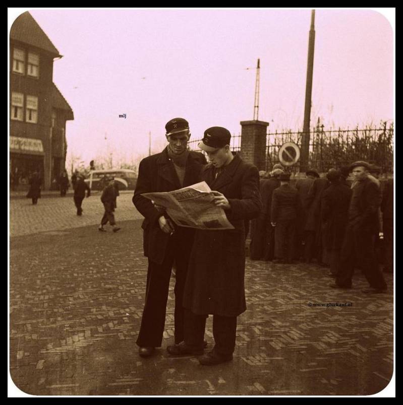 Mijnwerkers lezen buiten de Mijn de krant in 1945. De 2 personen die de krant lezen zijn Loc.machinisten van de Stm. Emma. © www.gluckauf.nl