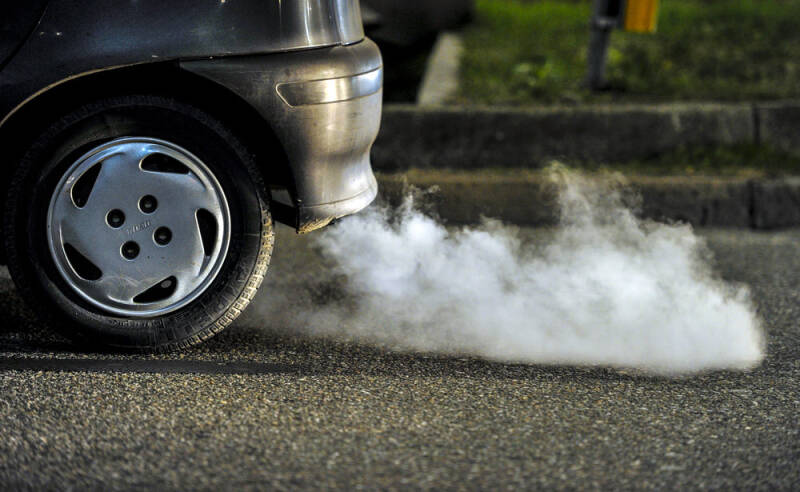 Car exhaust emitting thick white smoke, indicating potential engine issues such as a head gasket leak, cracked engine block, or damaged cylinder head