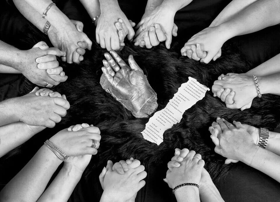 Handen die elkaar vasthebben in een circel met een hand in het midden