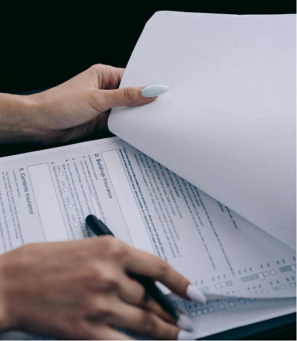Person reviewing and signing financial documents with pen