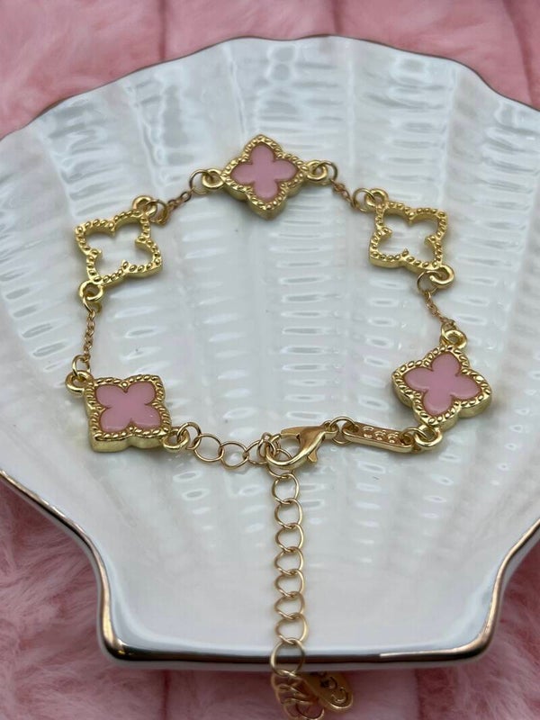 Goudkleurige armband met open en roze klavertjes