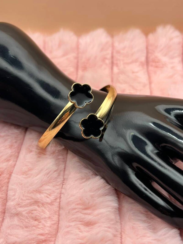 Goudkleurige bangle armband met zwarte bloemklavers