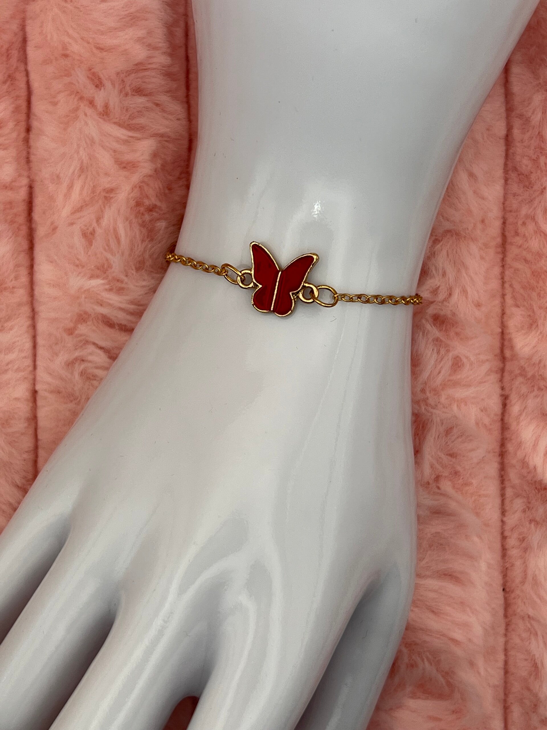 Goudkleurige armband met rode vlinder