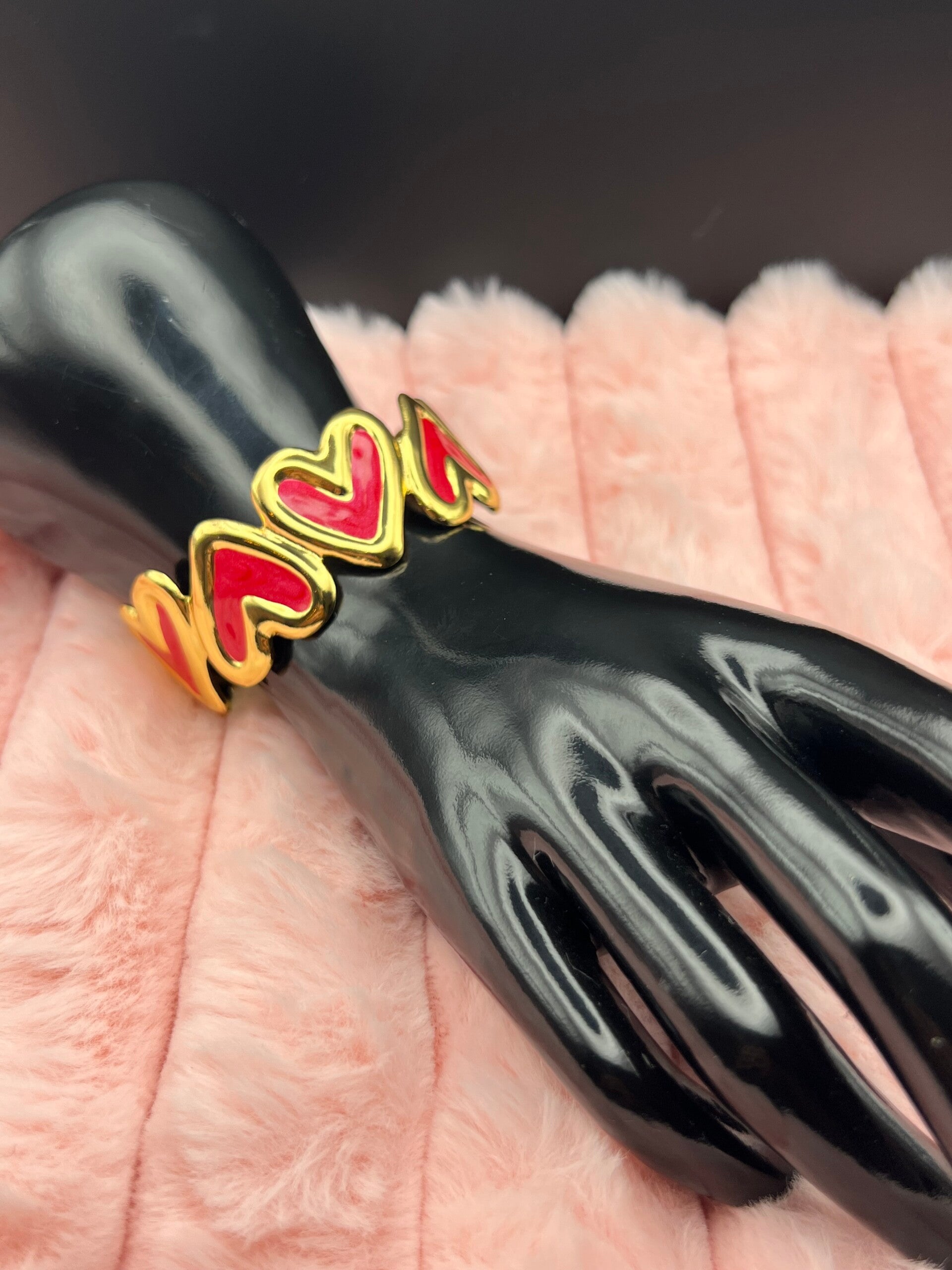 Goudkleurige bangle armband met rode hartjes