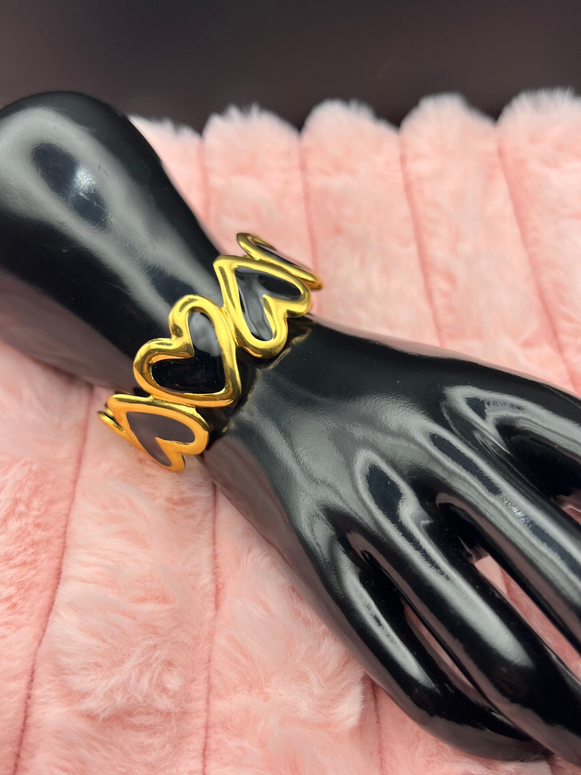 Goudkleurige bangle armband met zwarte hartjes