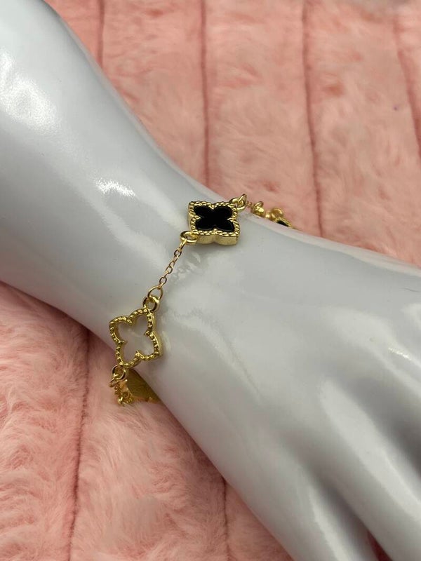 Goudkleurige armband met open en zwarte klavertjes