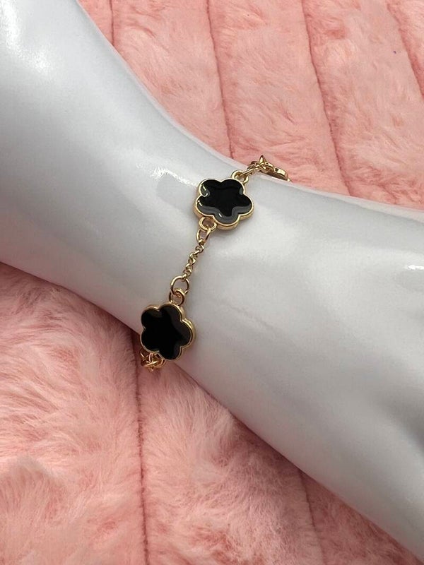 Goudkleurige armband met zwarte bloemklavers