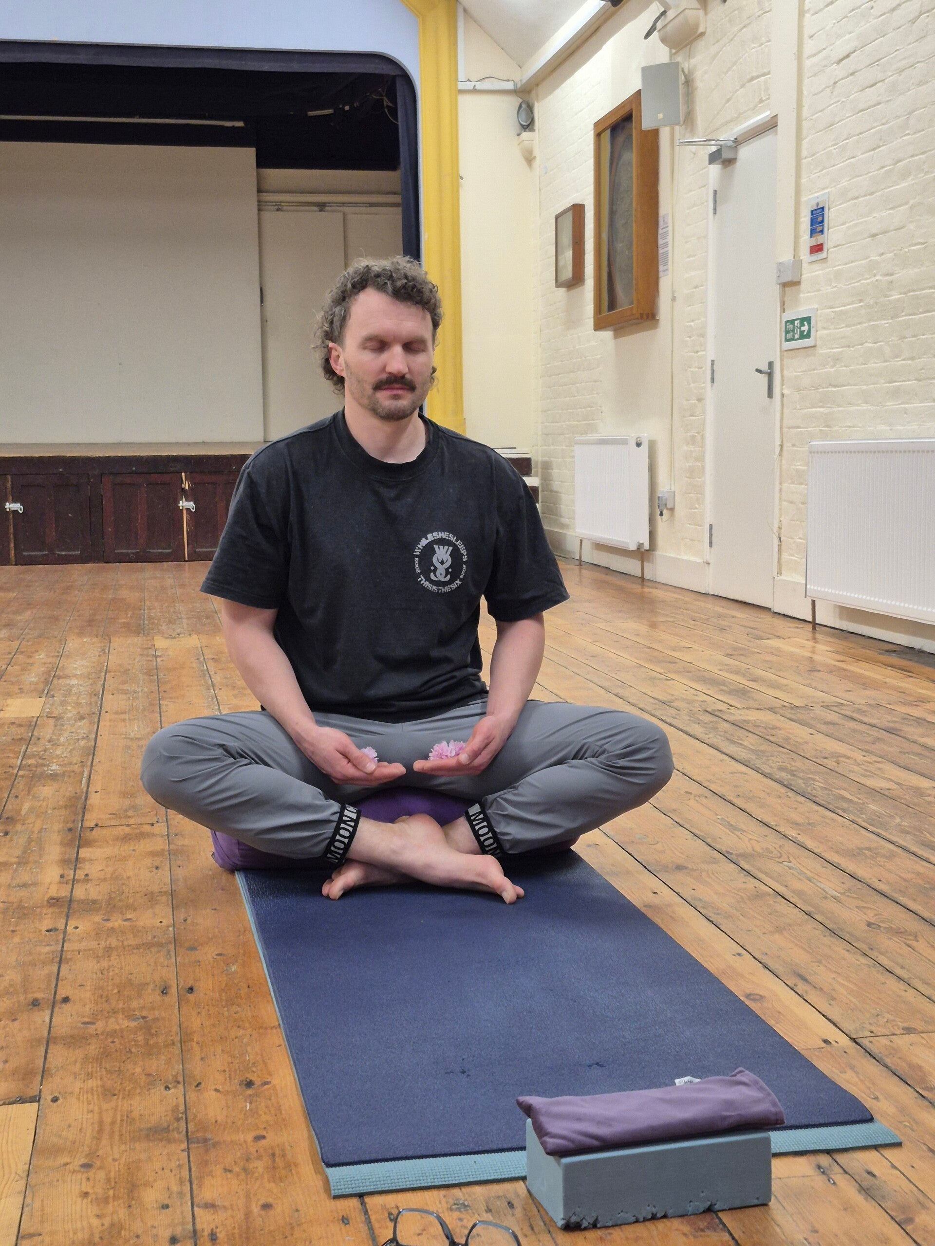 Picture of a very relaxed cat lying on its back a top of a yoga mat, sleeping