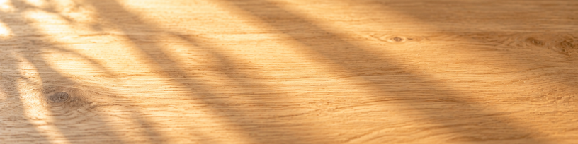 Table en bois clair traversée par une lumière dorée