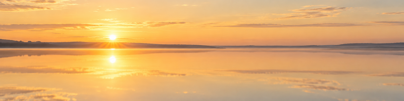 Surface d'eau calme au petit matin reflétant un ciel clair