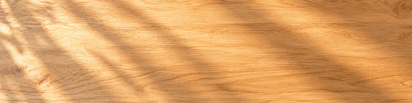 Table en bois clair vide traversée par une lumière dorée