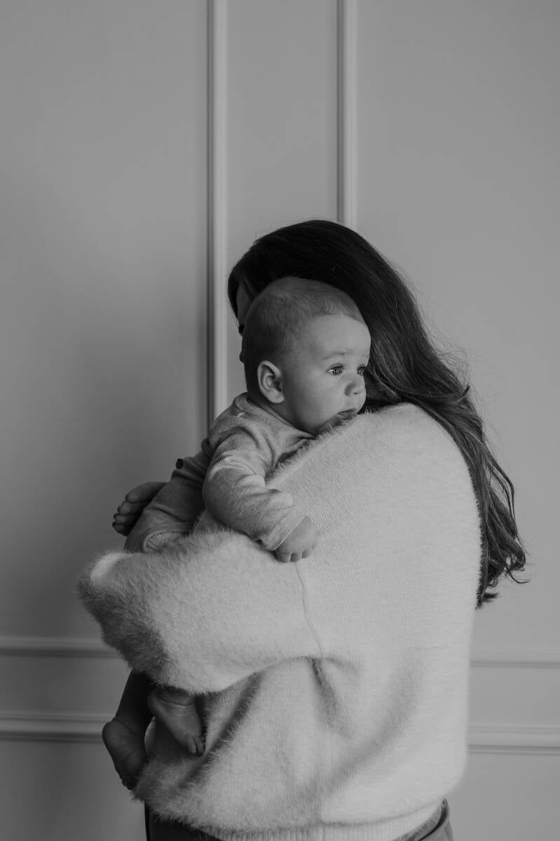 baby knuffelend met mama en kijkt voor zich uit
