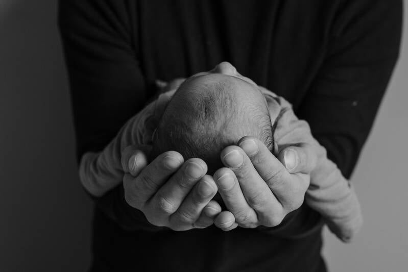 zwart wit foto van een pasgeboren baby gedragen in handen