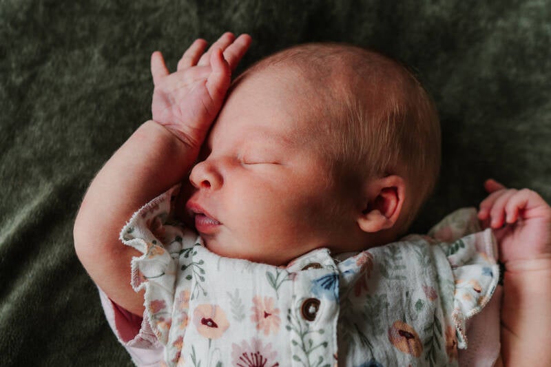 kleurenfoto van slapende pasgeboren baby met hand voor gezicht