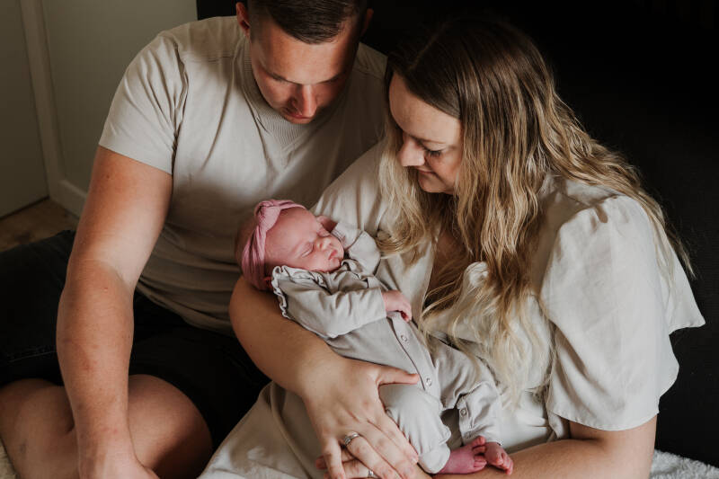 vader en moeder poserend met pasgeboren baby zittend op bed