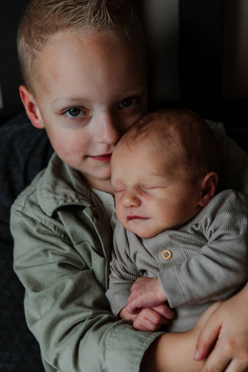 grote broer met pasgeboren baby in armen