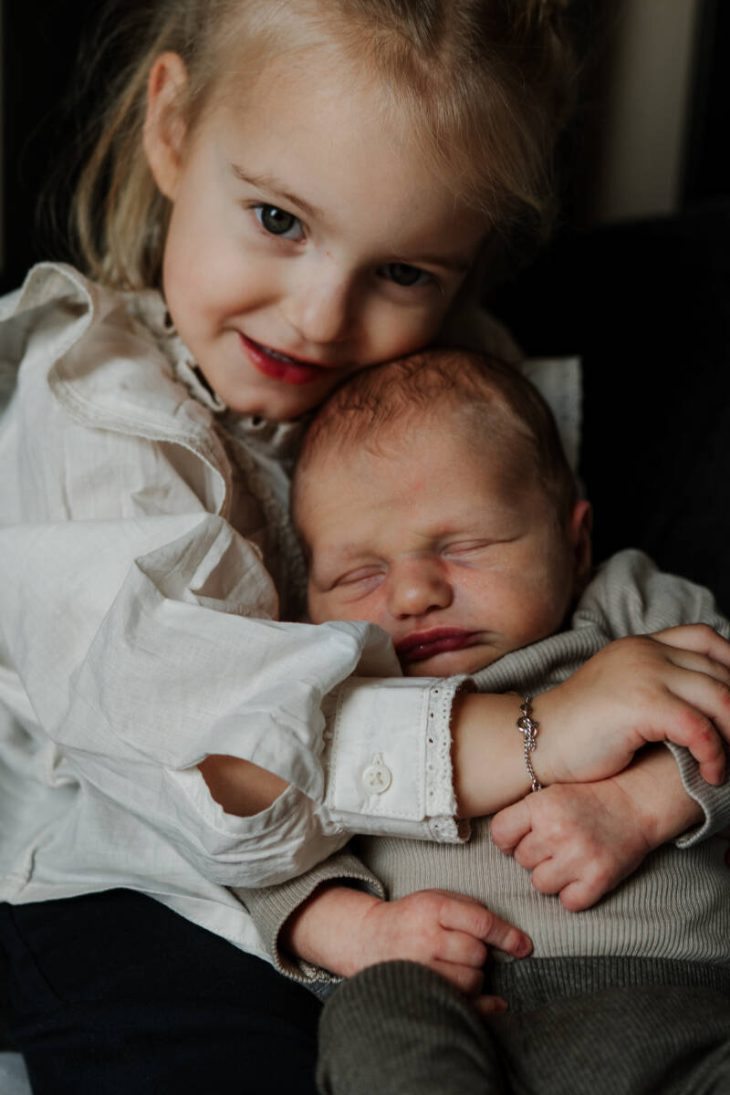 grote zus met pasgeboren baby in armen