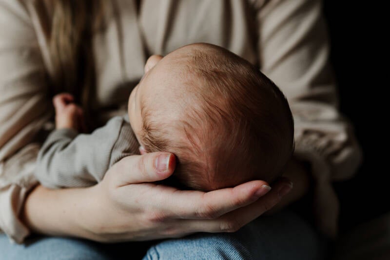 pasgeboren babyhoofdje gefotografeerd in de handen van mama