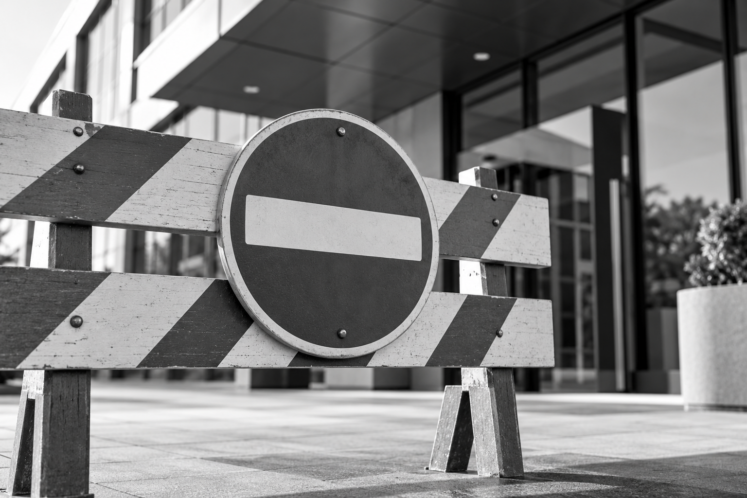 Zwart-witte wegafzetting met een verboden-toegangsbord voor de ingang van een modern kantoorgebouw.
