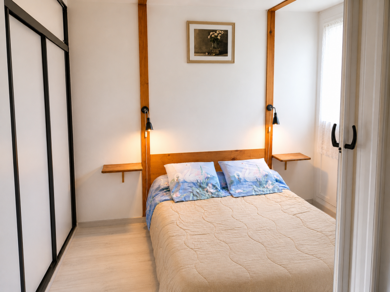 Chambre parentale avec lit double, armoire-penderie à portes coulissantes et séparation préservant l'intimité.