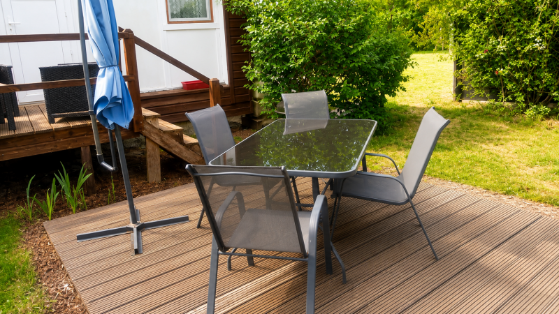 Terrasse privative avec espace repas, salon de détente et grand parasol pour profiter pleinement des beaux jours en Sologne.