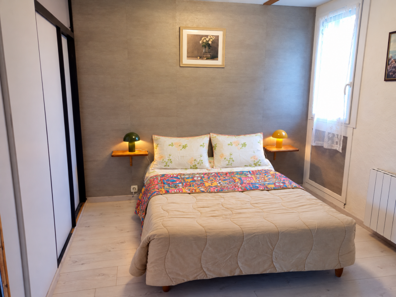 Chambre parentale avec lit double, armoire-penderie à portes coulissantes et séparation préservant l'intimité.