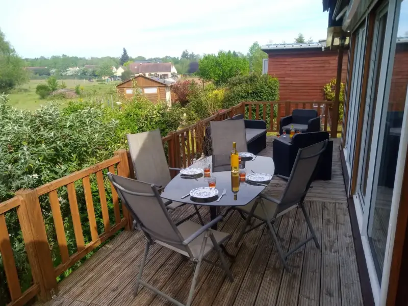 Grande terrasse d’un gîte en Sologne avec table extérieure dressée, salon de jardin et vue sur la nature à Nouan-le-Fuzelier proche Lamotte-Beuvron