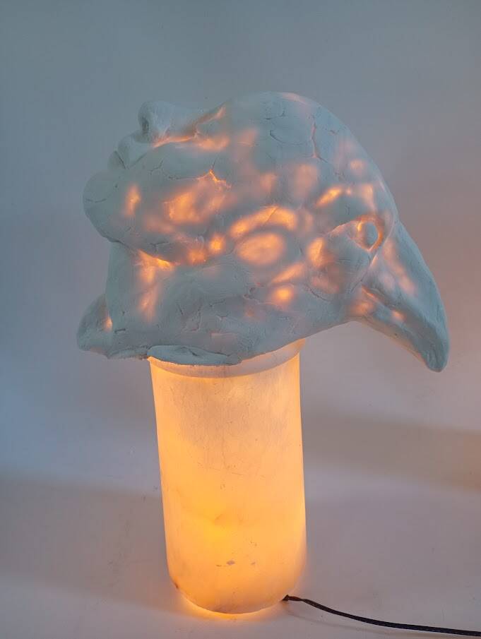 hier zie je een lichtsculptuur op een marmeren sokkel. De ene kant is een vrouw, de andere kant een vogel 