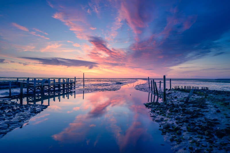 Kleurrijke landschapsfoto van Het haventje van Sil in de Cocksdorp van Texel tijdens eb bij zonsopkomst.