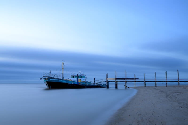 Long exposure foto van het waddenveer, de Vriendschap, aan de steiger op Texel met een verstild effect in het zeewater door de lange sluitertijd.