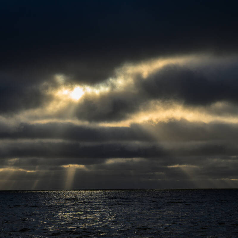 Prachtige zonnestralen die door het wolkendek breken boven een rustige noordzee