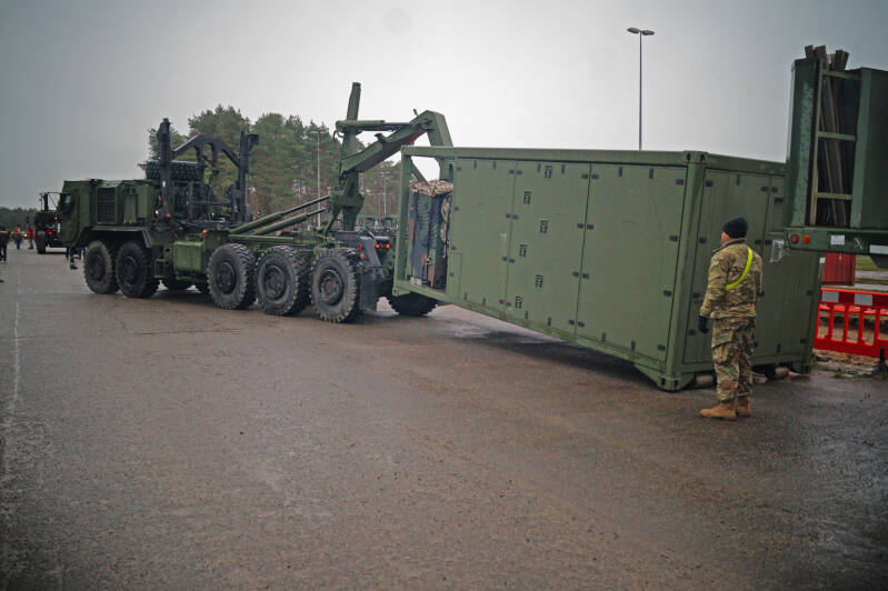 Met de haakarm word de container op de vrachtwagen gehezen.