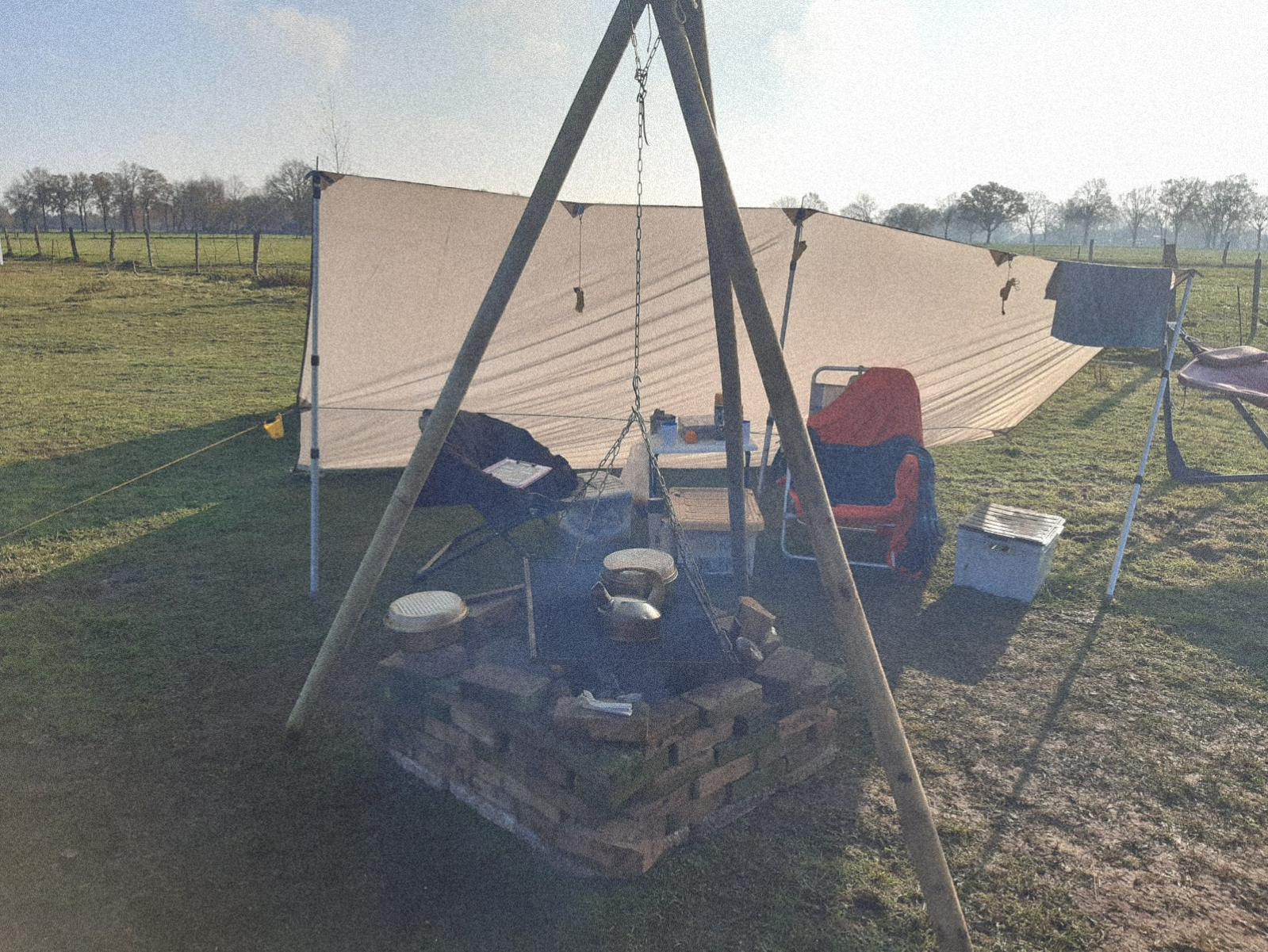 Kleine tentencirkel op een boerenerf met kookplek en tarp, voor een outdoor coaching- of workshopdag.