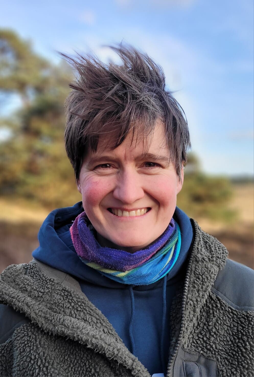 Vrouw die tijdens een coachwandeling pauzeert met een warme drank in een herfstbos, een moment van rust en reflectie in de natuur.