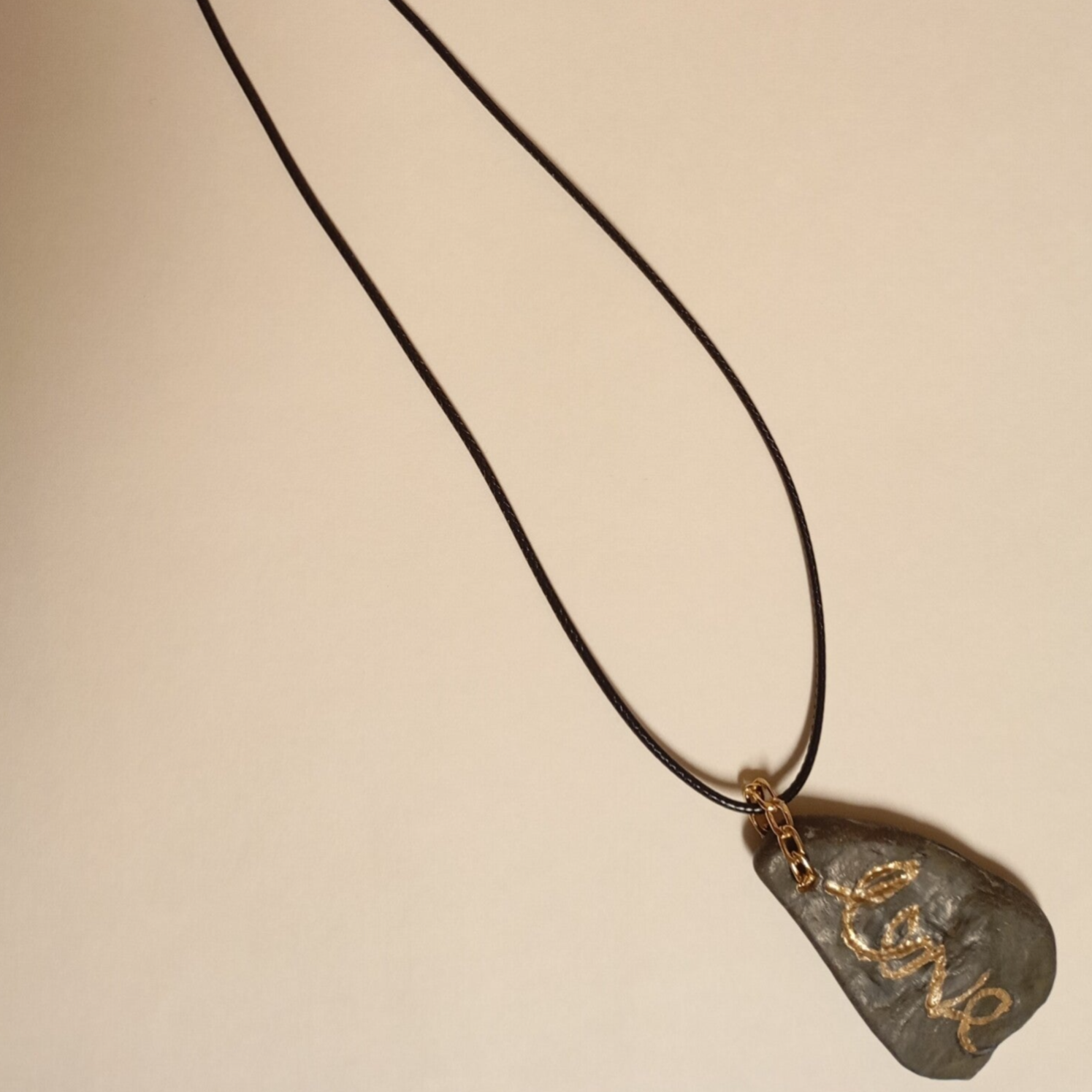 Halskette aus Naturstein mit eingravierter Goldinschrift.